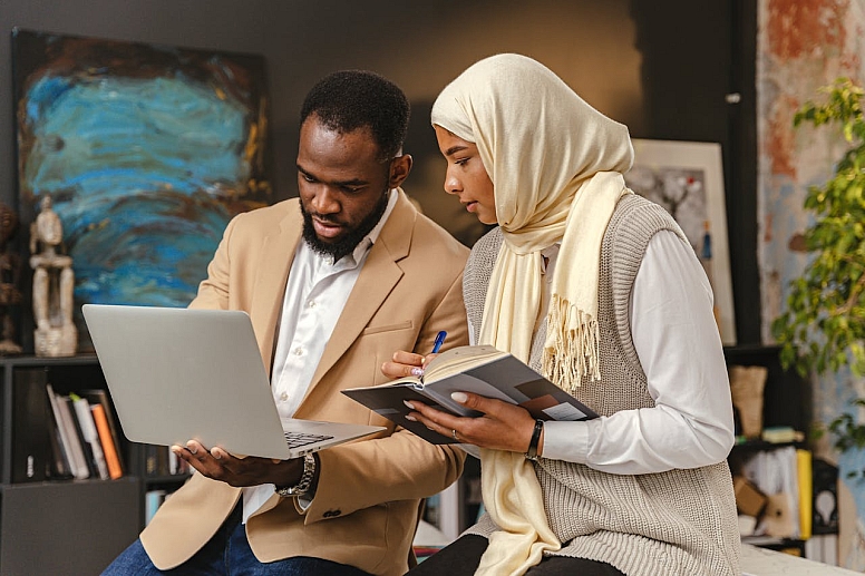 muslim man and a woman looking at a laptop